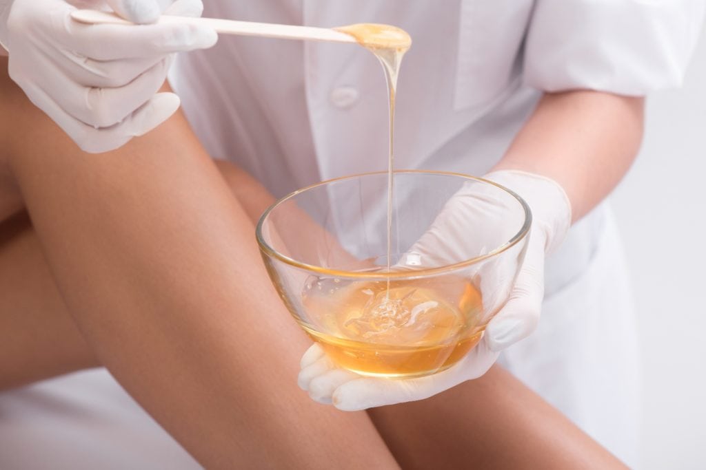 Softness from head to toe. Close up of beautician holding bowl of hot wax before starting procedure of depilation, isolated on white background